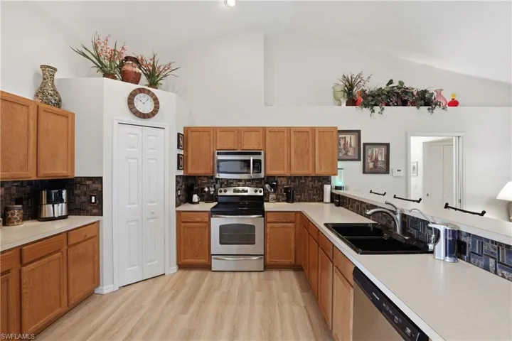 Kitchen with stainless steel appliances, light countertops, light wood-type flooring, tasteful backsplash, and wood finish cabinets