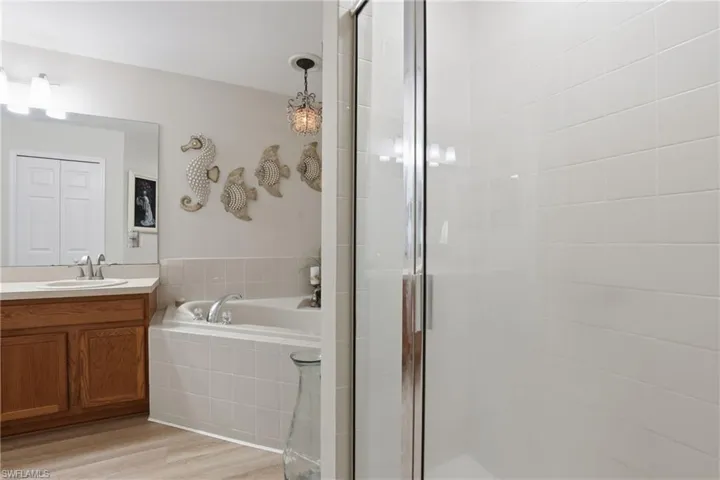 Full bathroom with vanity, light wood-style floors, a garden tub, and a shower stall