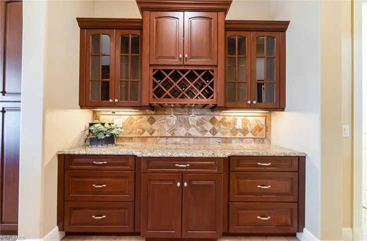 Bar featuring light stone counters and decorative backsplash