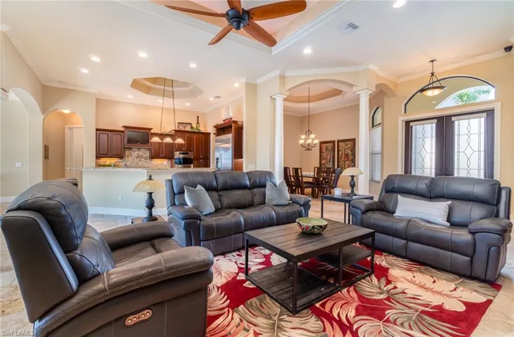 Living room with ornamental molding, a tray ceiling, ceiling fan