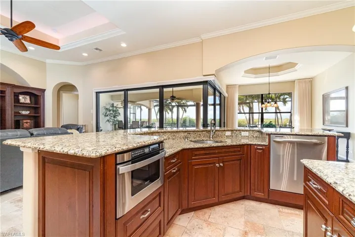 Kitchen with light stone counters, sink, a raised ceiling, and appliances with stainless steel finishes