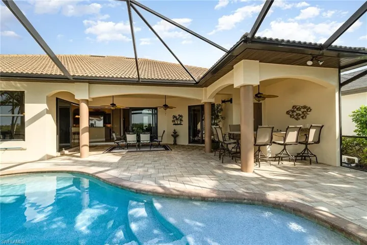 Rear view of house featuring a patio area, ceiling fan, and screen enclosure