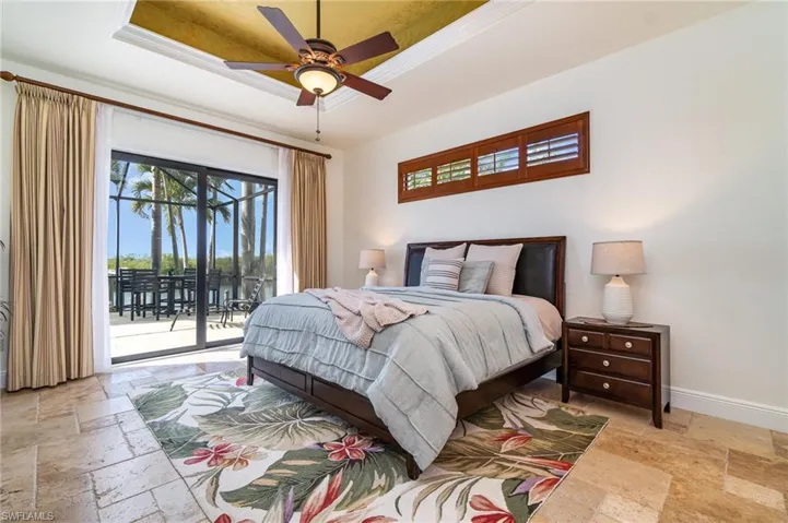 Bedroom featuring ceiling fan, ornamental molding, a tray ceiling, and access to outside