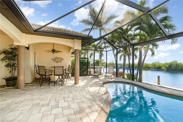 View of swimming pool featuring a lanai, a patio area, ceiling fan, and a water view