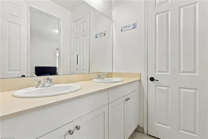 Double vanity with integrated sinks, chrome faucets, and white cabinetry