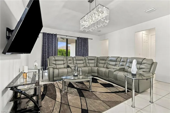 Recessed lighting, large format tile flooring, and a contemporary chandelier illuminate this space