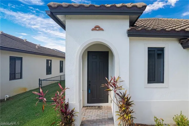 Stucco exterior with a tiled roof and dark gutters
