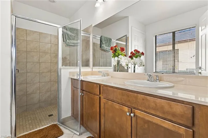Dual vanity with undermount sinks, warm wood cabinetry, and neutral-toned countertop