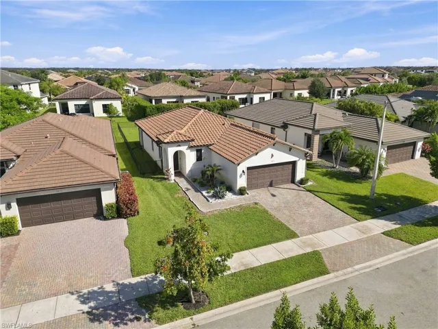 Mediterranean-inspired architecture featuring a terracotta tile roof, paver driveway, and a two-car garage