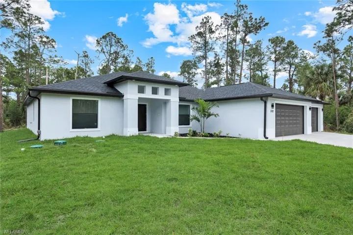 Prairie-style house with a front lawn, an attached garage, stucco siding, and concrete driveway