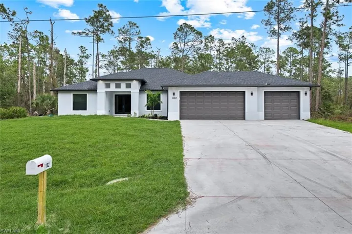 Prairie-style home with a front lawn, a garage, concrete driveway, stucco siding, and roof with shingles