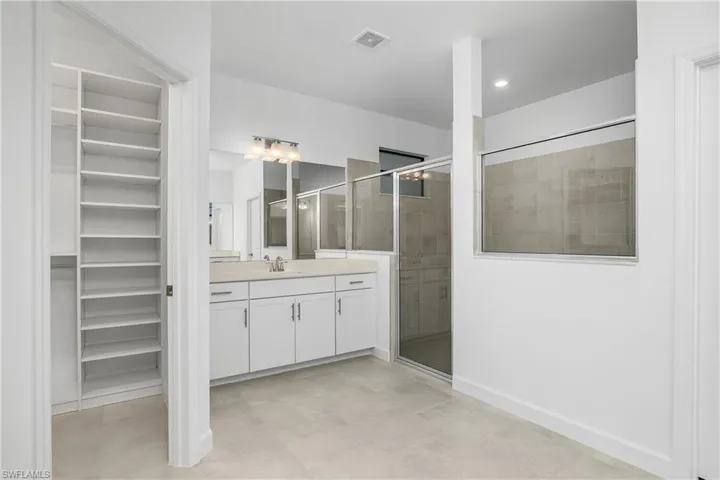 Primary bath features dual vanities, oversized walk-in shower, and his/hers closets with custom built-ins.