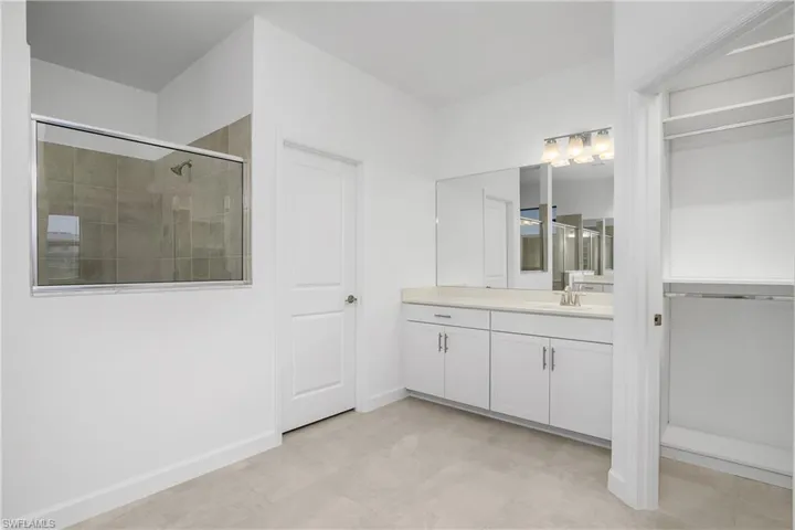 Primary bath with dual vanities/sinks, two walk-in closets with custom built in shelving, and large walk-in shower.