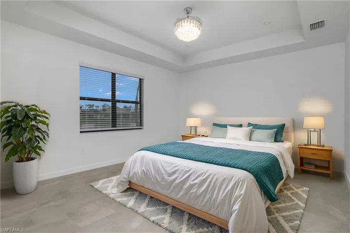 Primary bedroom is spacious and includes additional recessed lighting, chandelier/ceiling fan, and spa-like bath. (Furniture digitally added)