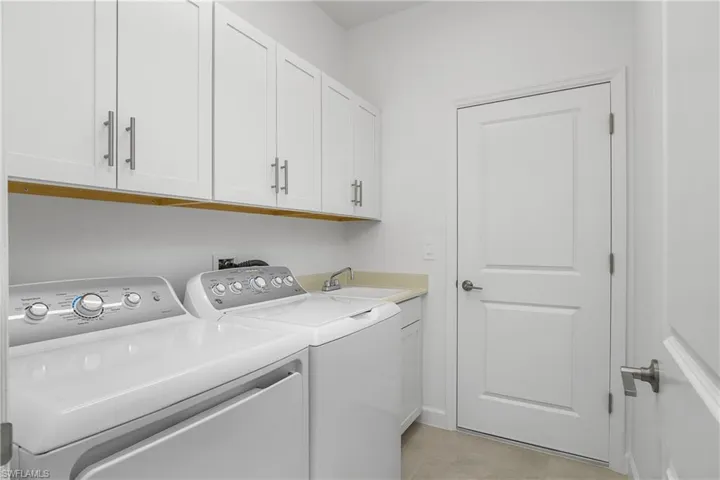 Laundry room features utility sink and additional upper cabinets for extra storage.