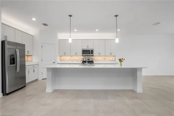 Kitchen includes custom backsplash, over and under cabinet lighting, oversized island, walk-in pantry, and stainless steel appliances.