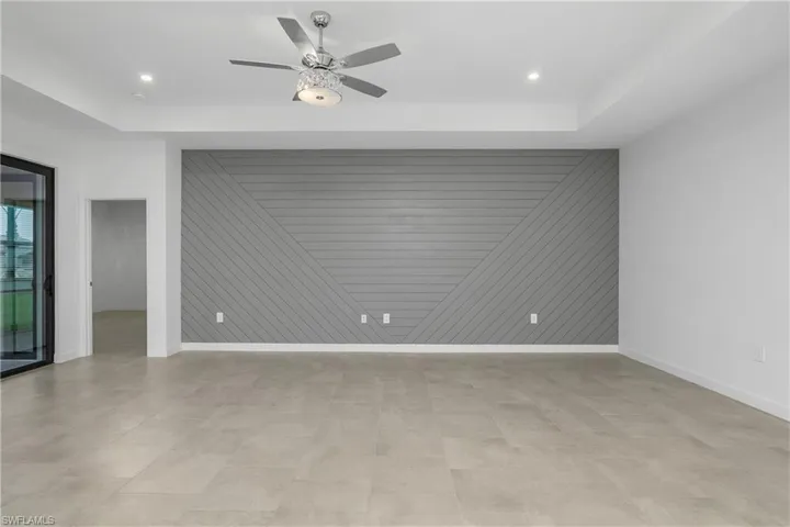 Empty room with ceiling fan and a tray ceiling