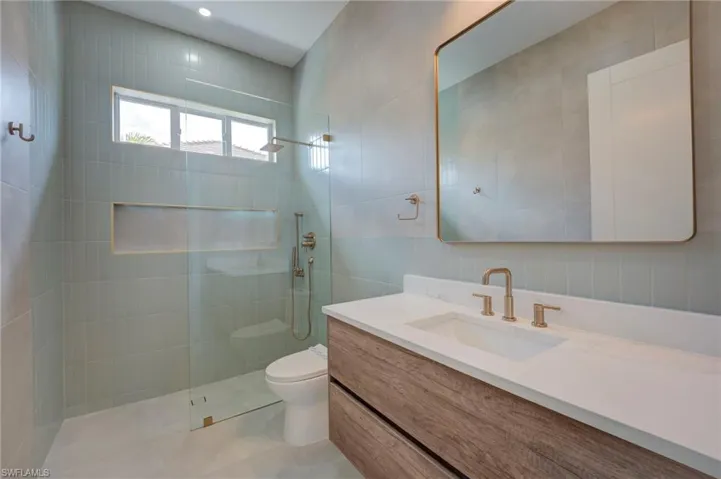 Bathroom with vanity, a walk in shower, and tile walls
