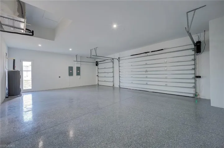 Garage with electric water heater, recessed lighting, and electric panel