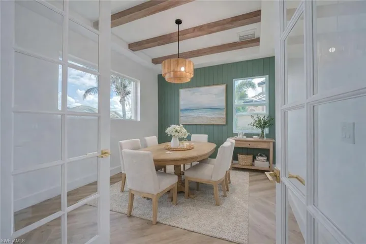 Dining space with light wood-type flooring, beam ceiling, wood walls, and an accent wall