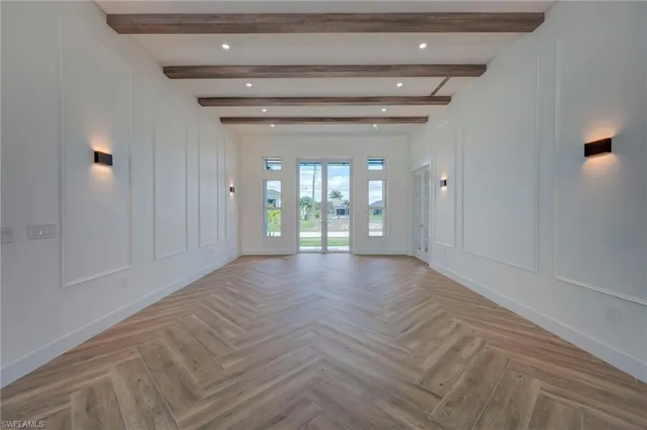 Empty room featuring a decorative wall, parquet flooring, and recessed lighting