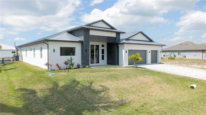 View of front of house with stucco siding, decorative driveway, an attached garage, and a front yard