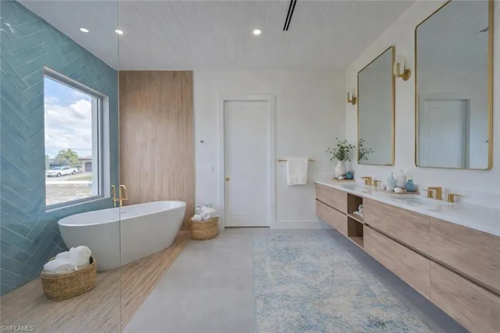 Bathroom featuring double vanity, a freestanding tub, recessed lighting, and wood ceiling