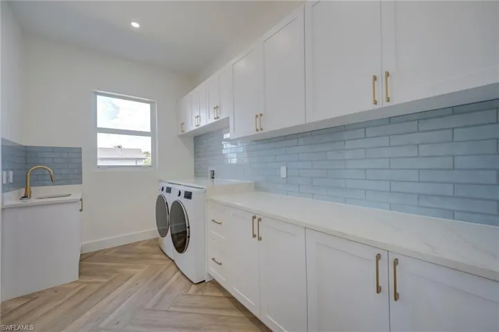 Laundry room featuring parquet flooring, washer and clothes dryer, cabinet space, and recessed lighting