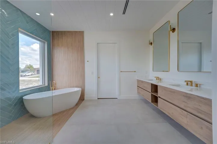 Full bath with double vanity, a freestanding bath, recessed lighting, wood walls, and wood ceiling