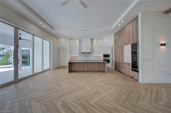 Two tone kitchen featuring modern cabinets, open floor plan, parquet floors, a large island with sink, and wooden ceiling