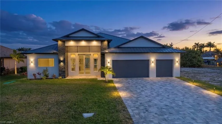 Modern home with a standing seam roof, a garage, decorative driveway, and a front yard