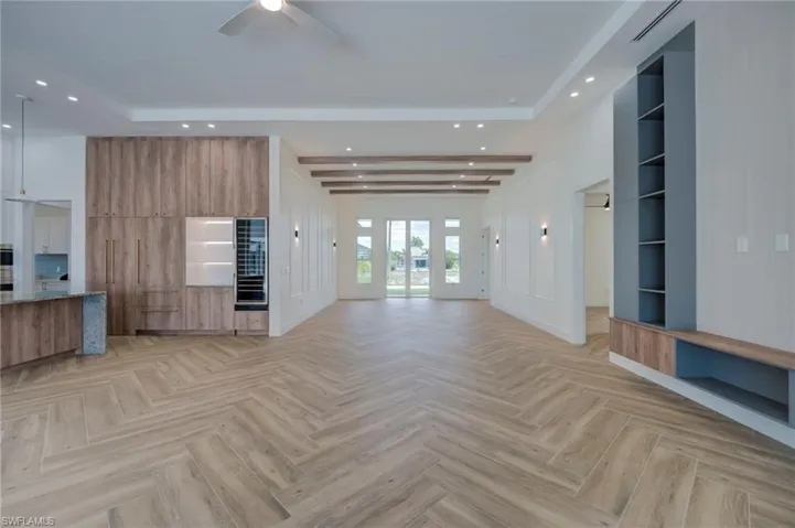 Unfurnished living room featuring a ceiling fan, recessed lighting, parquet floors, and a raised ceiling