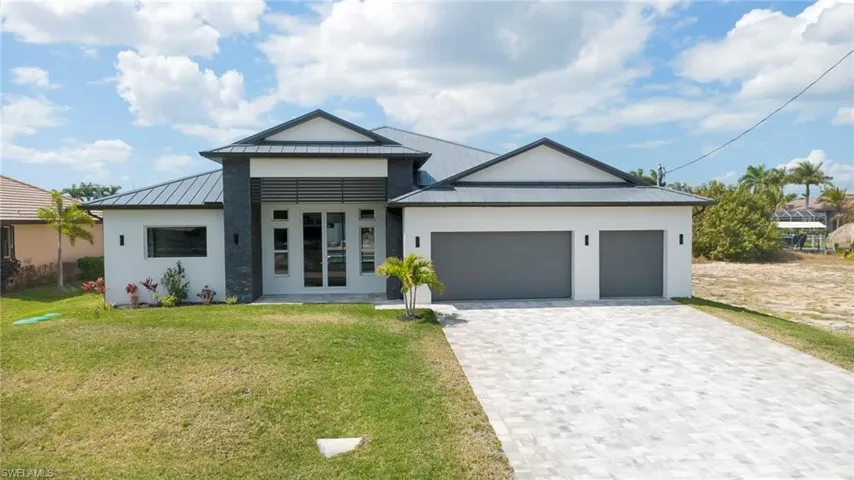 View of front facade featuring a standing seam roof, french doors, a garage, decorative driveway, and stucco siding