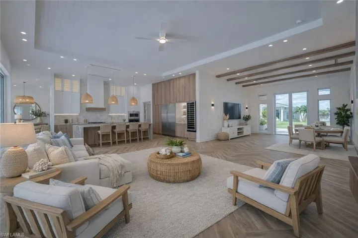 Living area with parquet floors, recessed lighting, ceiling fan, and a raised ceiling