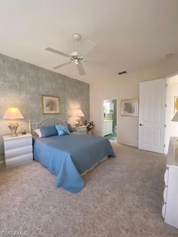 Bedroom featuring ensuite bathroom, carpet floors, and ceiling fan
