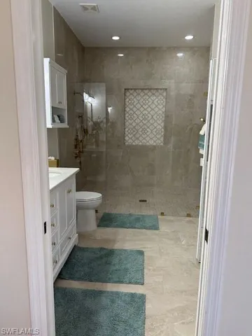 Bathroom with a tile shower, vanity, and toilet