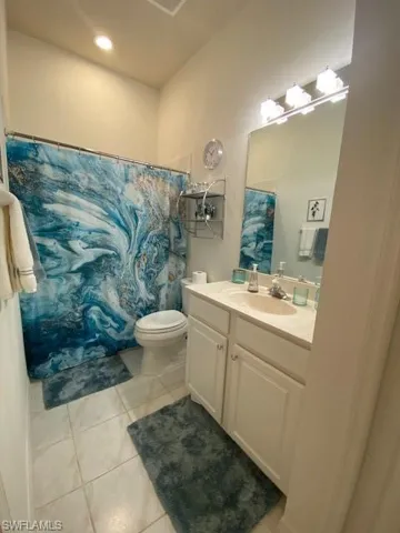 Bathroom with vanity, a shower with curtain, toilet, and tile patterned flooring
