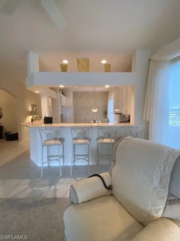 Kitchen with pendant lighting, refrigerator, light tile patterned floors, and a kitchen bar