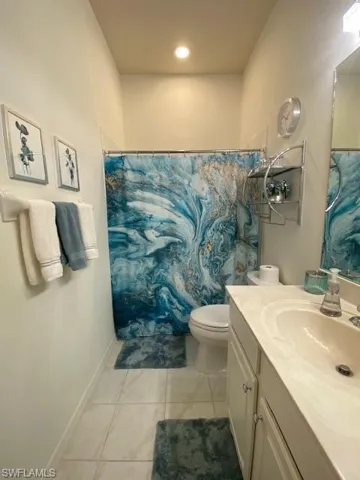 Bathroom with vanity, a shower with shower curtain, toilet, and tile patterned floors