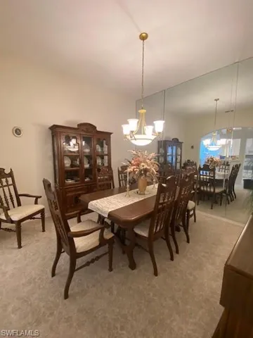 Carpeted dining area featuring an inviting chandelier