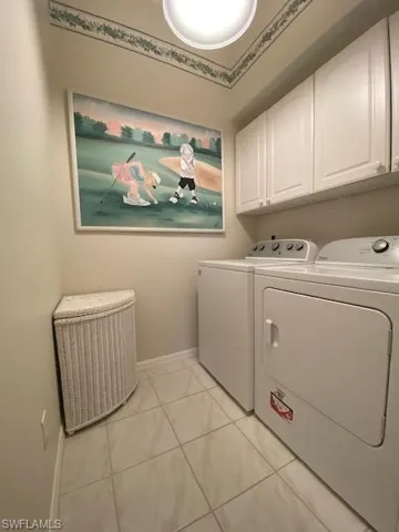 Clothes washing area featuring cabinets, independent washer and dryer, and light tile patterned floors