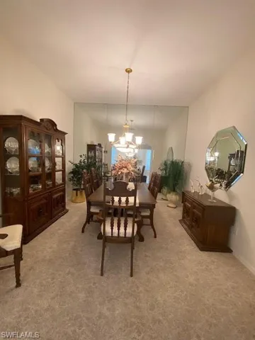 Carpeted dining room with an inviting chandelier