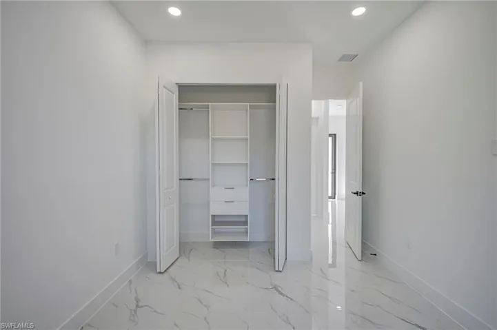 Unfurnished bedroom with recessed lighting, light marble finish floors, and a closet