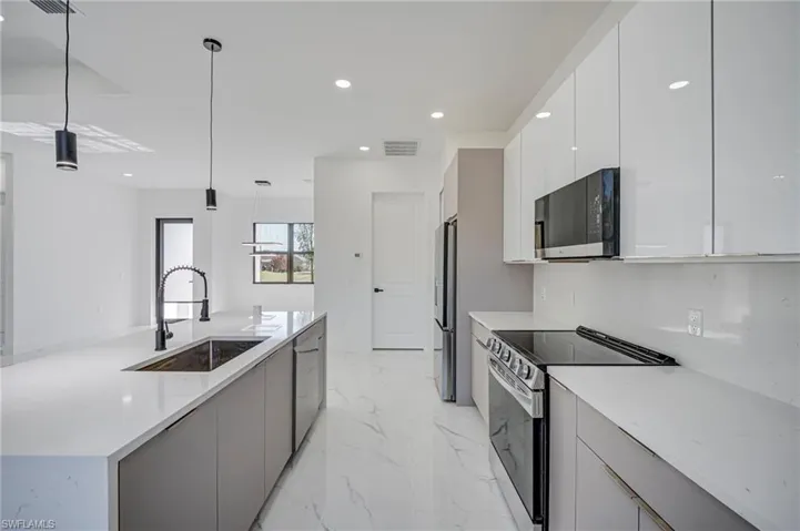 Kitchen featuring stainless steel appliances, light stone countertops, a large island, modern cabinets, and light marble finish floors