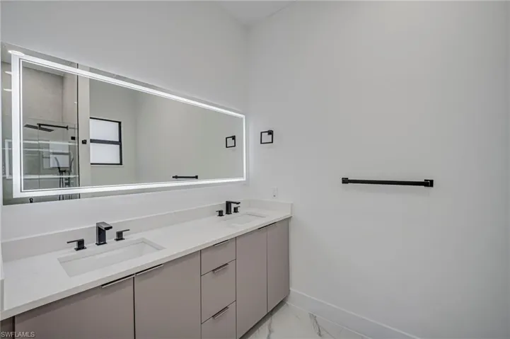 Full bathroom with double vanity and light marble finish flooring