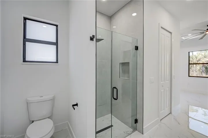 Full bathroom with a stall shower, recessed lighting, light marble finish flooring, and a ceiling fan