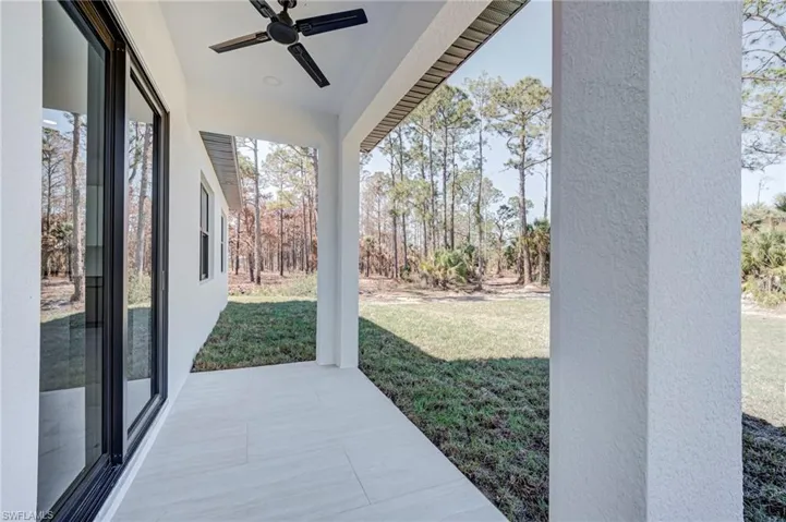 Covered patio with a black ceiling fan and recessed lighting, featuring large format tile flooring and a stucco exterior