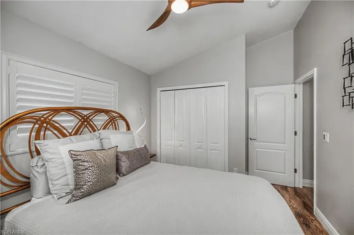 Bright primary bedroom featuring a wood-frame headboard, crisp white bedding, and coordinating accent pillows