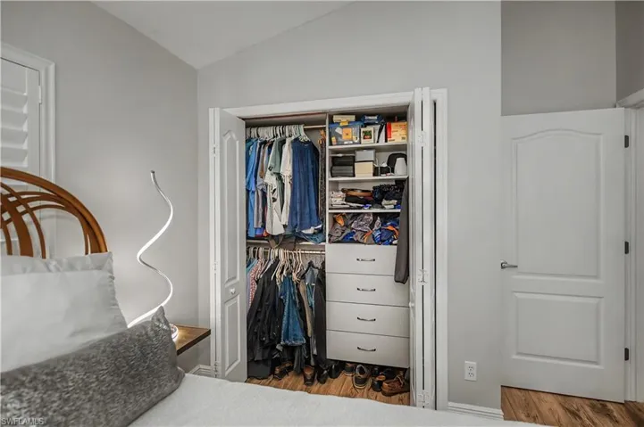 Integrated closet system with multiple shelving units and built-in drawers, complemented by a wood-finish floor