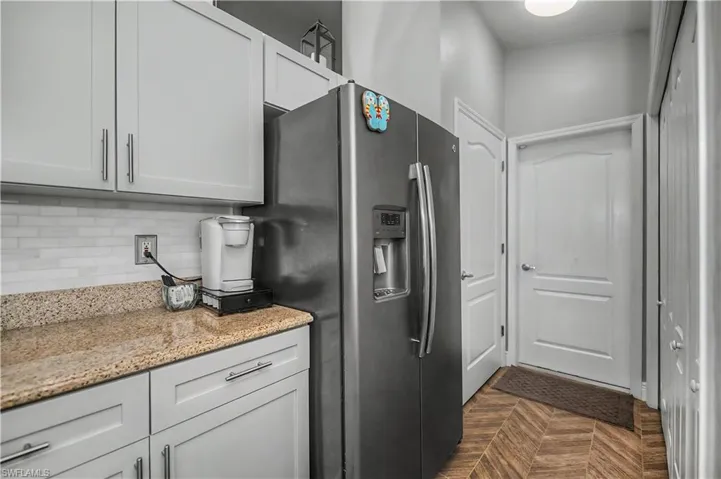 Modern kitchen area featuring light gray cabinetry with brushed nickel hardware, a light-toned granite countertop, and a white subway tile backsplash